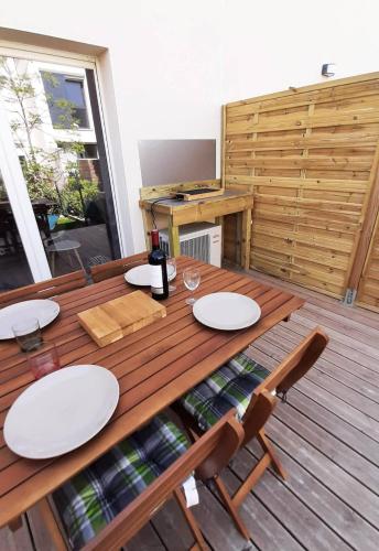 - une table en bois avec des assiettes et des verres à vin sur une terrasse dans l'établissement Valras-Loc La Dune - Brise Marine Elegance Cotiere, à Sérignan