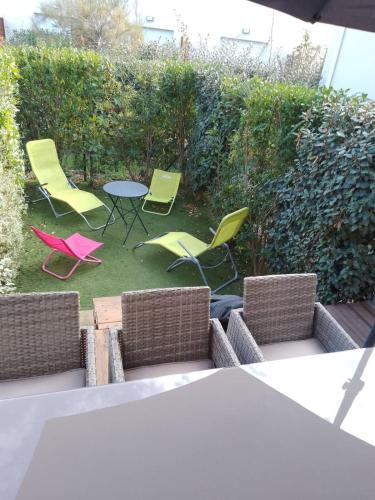 une terrasse avec des chaises vertes, une table et des chaises dans l'établissement Valras-Loc La Dune - Sejour Marin avec Piscine, à Sérignan