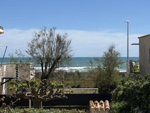 - une vue sur la plage depuis une maison avec un arbre dans l'établissement Valras-Loc - Maison bord de mer 2 terrasses, à Valras-Plage