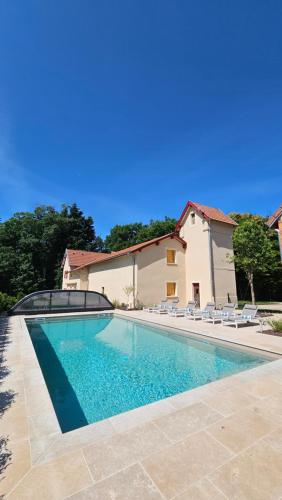 une piscine avec des chaises et une maison dans l'établissement Cottage de Montchamp, à Châtenay