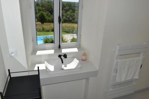 une salle de bain blanche avec un lavabo et une fenêtre dans l'établissement Les Granges, à Marquay