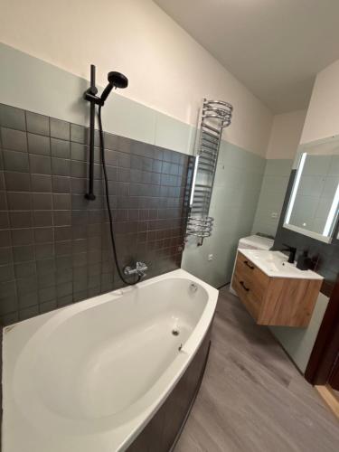 a white bath tub in a bathroom with a sink at Apartman Orlí hnízdo in Liberec