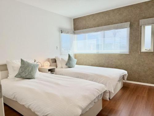 a bedroom with two beds and a window at Akikawa Miyoshi 7 in Kumamoto
