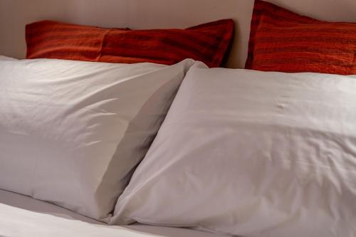 a bed with white sheets and red pillows at Borgo delle Botteghe Luxury Suites in Parma