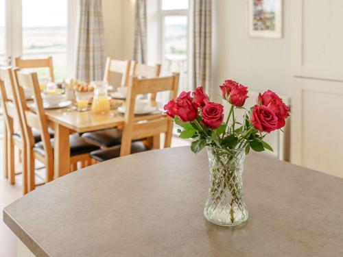 a vase filled with red roses sitting on a table at 3 Bed in St Andrews 88420 in Balmullo