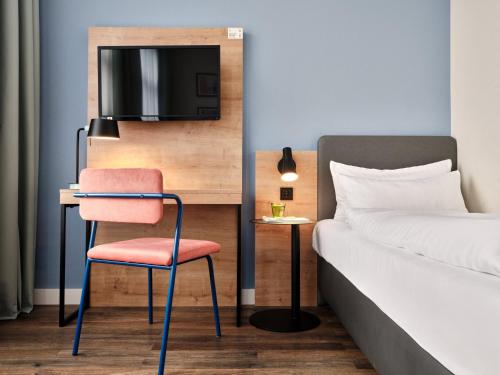 a bedroom with a desk and a chair next to a bed at Garner Hotel Berlin - Schöneberg by IHG in Berlin