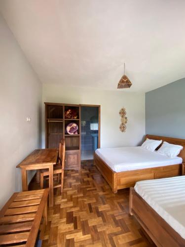 a bedroom with two beds and a table and a desk at Andasibe Sifaka Lodge in Andasibe