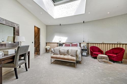 a bedroom with a bed and a desk and red chairs at Luxurious subterranean mansion - 3 spectacular bedrooms in Altrincham