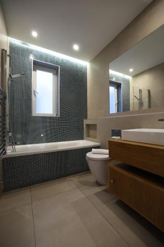 a bathroom with a tub and a toilet and a sink at STYLISH 3 BED Partial SEAVIEW in St. Julianʼs