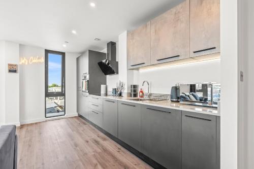 a kitchen with gray cabinets and a wooden floor at York Penthouse with Hot Tub & View of Minister in York