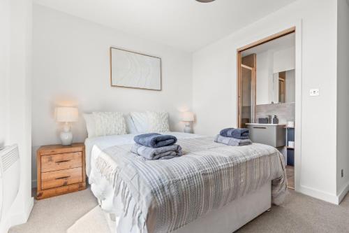 a white bedroom with a bed with blue towels on it at York Penthouse with Hot Tub & View of Minister in York