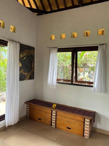 a room with a wooden bench and two windows at Rumah Tenun in Karangasem