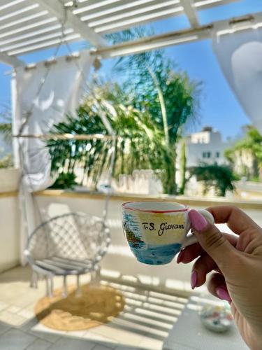 a person holding a cup on a table at Dimora Il Girasole in Torre San Giovanni Ugento