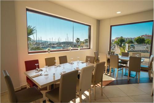 a dining room with a table and chairs and a large window at Ohtels Campo De Gibraltar in La Línea de la Concepción
