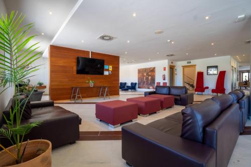 a living room with leather furniture and a flat screen tv at Ohtels Campo De Gibraltar in La Línea de la Concepción