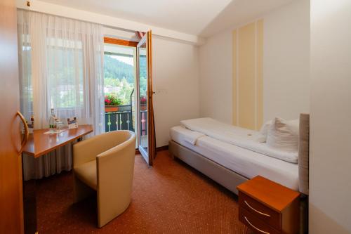 a bedroom with a bed and a desk and a window at Wellnesshotel Rothfuß mit Spa und 2 Schwimmbädern in Bad Wildbad