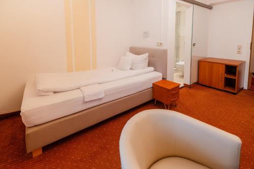 a bedroom with a large bed and a chair in it at Wellnesshotel Rothfuß mit Spa und 2 Schwimmbädern in Bad Wildbad