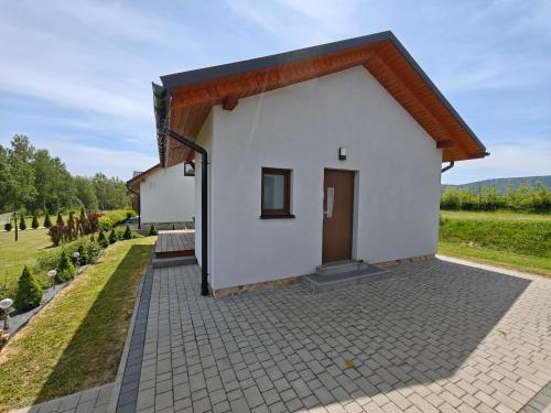 a small white house with a driveway at Na wilczym szlaku in Ustrzyki Dolne