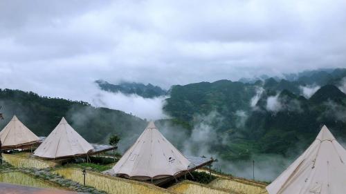 a group of tents with mountains in the background at Sunrise Camping Ha Giang Lung Cu in Ha Giang