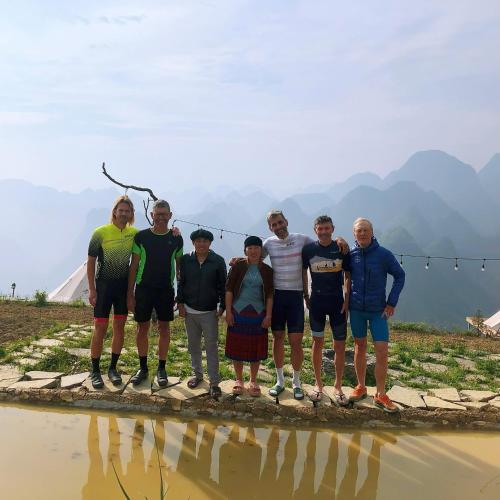 a group of people posing for a picture on a bridge over a river at Sunrise Camping Ha Giang Lung Cu in Ha Giang