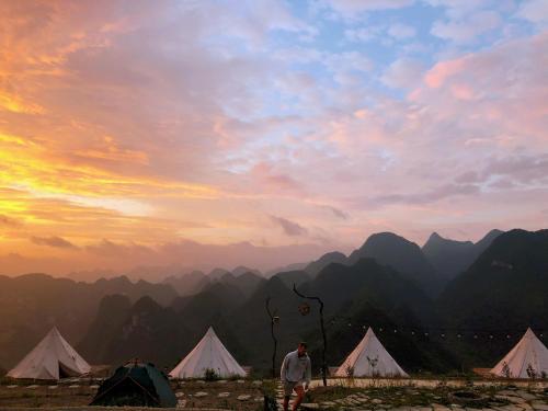 a man standing in front of tents and mountains at Sunrise Camping Ha Giang Lung Cu in Ha Giang