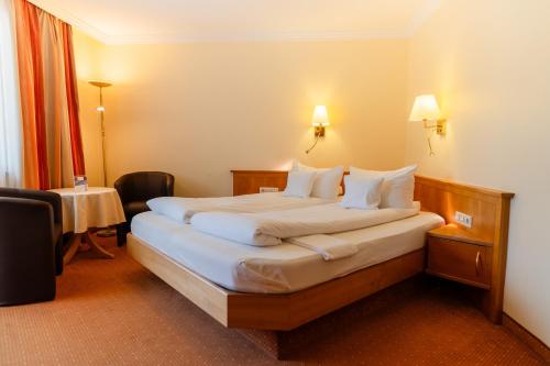 a hotel room with a large bed with white pillows at Wellnesshotel Rothfuß mit Spa und 2 Schwimmbädern in Bad Wildbad