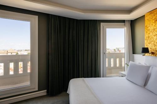 a bedroom with a bed and a large window at Hotel Colón Gran Meliá - The Leading Hotels of the World in Seville