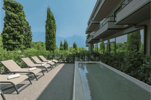 a row of lounge chairs next to a swimming pool at Hotel Royal Village in Limone sul Garda