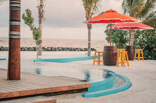 a beach with chairs and an umbrella on the beach at Oaga Art Resort Maldives - Greatest All Inclusive Plan with Free Speedboat Round-trip in North Male Atoll
