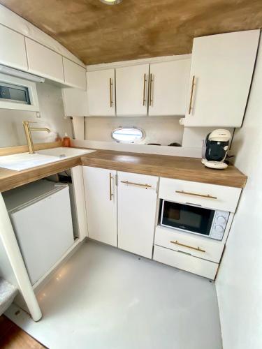 une petite cuisine avec des armoires blanches et un évier dans l'établissement BOAT PARADISE LA ROCHELLE - Cranchi Méditerranée 40, à La Rochelle