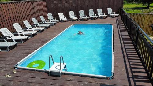 a person swimming in a swimming pool with chairs at Bilychi - садиба у Карпатах in Bilichi