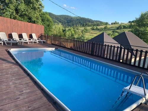 a swimming pool with chairs on a wooden deck at Bilychi - садиба у Карпатах in Bilichi