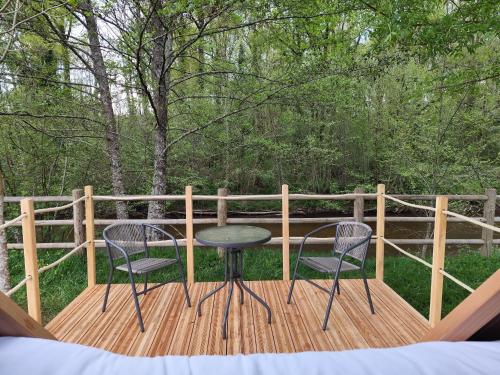 two chairs and a table on a wooden deck at Friendly Camping and Lodges in Saint-Pardoux-la-Rivière