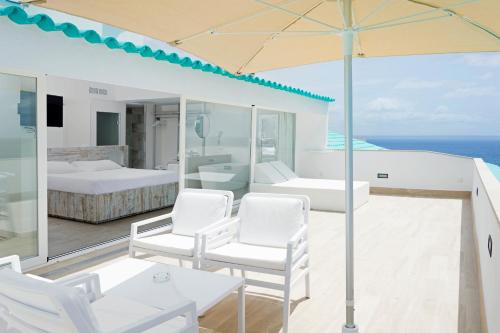een wit huis met witte stoelen en een paraplu bij HSM Sandalo Beach in Magaluf