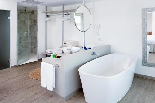 a white bathroom with a tub and a mirror at HSM Sandalo Beach in Magaluf