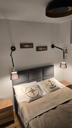 a bedroom with a bed with two lights on the wall at Apartament na wydmie B9 in Łeba