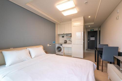 a bedroom with a white bed and a kitchen at The November Stay In landmark in Incheon