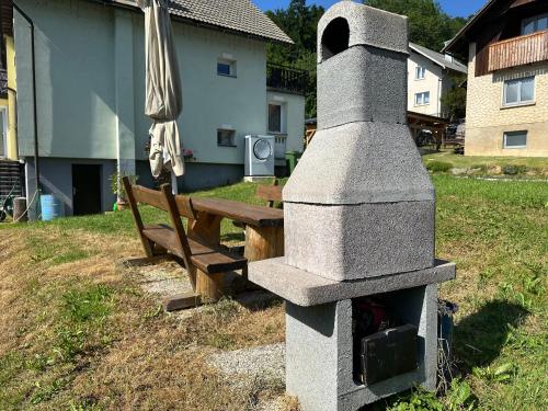 a stone oven next to a bench and an umbrella at Apartma Rekar - a house, where you can relax in the embrace of nature in Jesenice