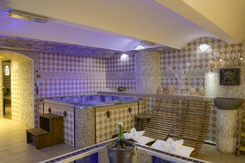 a purple room with a tub and a tile wall at Wellness Hotel Beethoven in Chomutov
