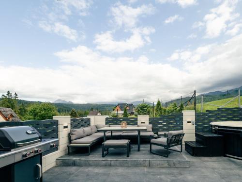 a patio with a table and chairs and a grill at Góralski Harem Osada Glamp & Glass z Jacuzzi i Balią in Zakopane