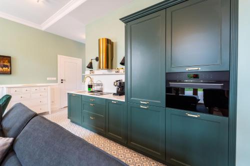 a kitchen with blue cabinets and a blue couch at Apartamenty Galeria Trunków in Białowieża