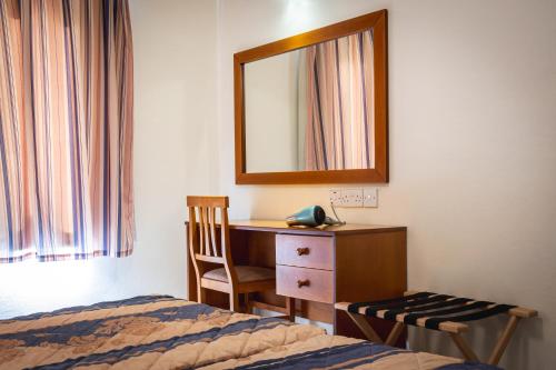 a bedroom with a bed and a desk and a mirror at Kefalos Damon Hotel Apartments in Paphos City