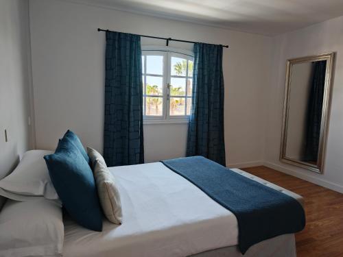 une chambre avec un lit avec des oreillers bleus et une fenêtre dans l'établissement Apartamentos San Marcial, à Tías