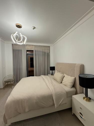 a white bedroom with a bed and a chandelier at 3403!Dubai SkyLine View! Royal Montania Homes in Dubai