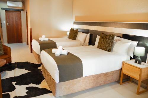 a hotel room with two beds and a chair at Silverlakes Farm Hotel in Pretoria