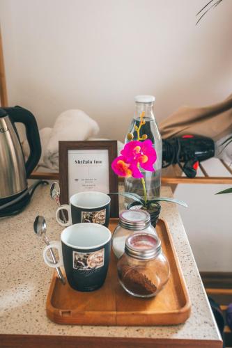 a tray with two cups and a flower and a bottle at GuestHouse "Shtëpia ime" in Përmet