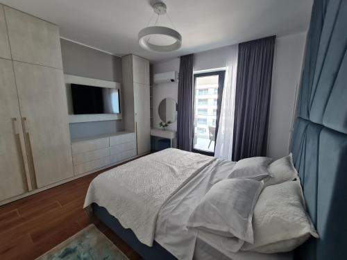 a bedroom with a bed and a tv and a window at Residence Sole by Axxis Nova Resort - Apartament luxury 70mp cu terasa si vedere la mare, acces direct pe plaja Axxis Beach BluFlag - Mamaia Nord - Parcare gratuita in Mamaia