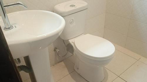 ein weißes Badezimmer mit Toilette und Waschbecken in der Unterkunft Shalom Wellspring Cottage in Malindi