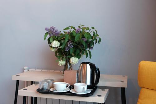 a table with two cups and a tea kettle and a vase of flowers at Beeography guest house in Vardablur