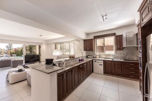 una cocina con armarios de madera y electrodomésticos blancos en Villa Adalia, en Protaras